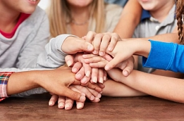Kinderhände als Symbol für Gemeinschaft Mehrere Kinder legen ihre Hände gemeinsam übereinander. © Canva