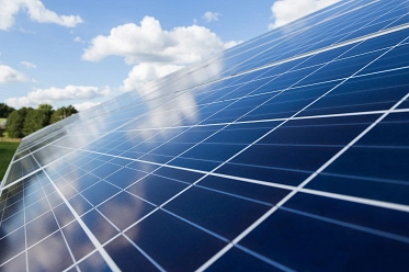Nahaufnahme von Photovoltaikmodulen unter blauem Himmel mit Wolken.